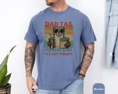 Photo 6 of 8: Athletic man leaning on a mountain bike wearing a garment dyed unisex dad weasel shirt featuring a retro weasel character and bold Dad Tax design, funny dad tee with faded vintage colors, cozy casual look perfect as a dad gift shirt or fathers day novelty for dad life lovers