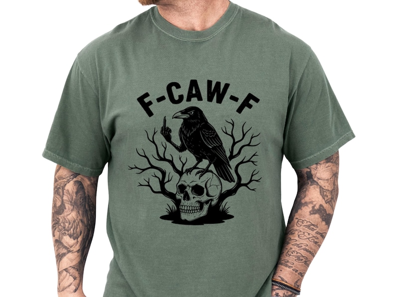 Unisex crow shirt in muted green with a bold black raven perched over a skull and bare branches, featuring the playful F-CAW-F design for fans of dark humor tshirt style and gothic crow tee looks, great as a sarcastic tee or gift for men