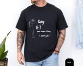 Photo 3 of 8: Black stick figure tee on a relaxed male model showing a white minimalist stick-figure and playful script Say 6-7 one more time, I dare you — a humorous I dare you shirt ideal as a school teacher gift, parent gift tee or gag gift, youthful casual 6 7 t shirt with cozy cotton feel