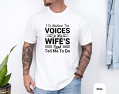 Photo 4 of 8: White unisex humor tee on a tattooed model, soft lightweight cotton with bold black printed slogan saying I do whatever the voices in my wife's head tell me to do, a wife voices shirt and funny marriage tee, perfect husband humor shirt and gag gift for anniversaries