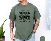 Photo 5 of 8: Smiling tattooed man modeling a moss green vintage wash shirt, a wife voices shirt with bold black slogan "I do whatever the voices in my wife's head tell me to do" — a unisex humor tee and funny husband shirt with cozy soft cotton feel, perfect gag gift for married life