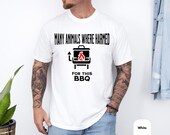 Photo 4 of 8: Crisp white tee worn by a casually dressed man, bold black lettering with the playful typo "Many Animals Where Harmed" above a red-flame grill icon — this many animals shirt is a funny BBQ shirt with dark humor and meme vibes, a typo shirt and cookout grilling shirt ideal as a bbq gift idea or meat lover gift for backyard barbecues