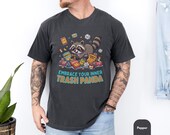Photo 2 of 14: Charcoal unisex t shirt featuring a playful raccoon bursting from colorful snack wrappers with the cheeky slogan Embrace Your Inner Trash Panda, a funny animal tee and raccoon t shirt with soft vintage wash, ideal trash panda shirt as a cute novelty graphic tee and animal lover gift for him