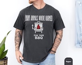 Photo 2 of 8: Soft faded charcoal cotton tee on a tattooed model, featuring a simple grill icon and the playful typo slogan 'Many animals where harmed' — a dark humor tshirt and funny bbq shirt that's a sarcastic grilling shirt and barbecue tee, meme tshirt and cookout shirt, great bbq gift idea or meat lover gift