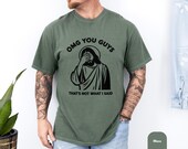 Photo 5 of 8: Moss green vintage wash tee with a bold black meme graphic of Jesus facepalm and text OMG YOU GUYS that's not what I said, unisex funny tshirt in a relaxed cozy fit styled with jeans and tattoos, sarcastic graphic and dark humor novelty gift for christians