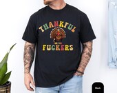 Photo 3 of 8: Casual unisex blue jean tee shown on a relaxed model, bright vintage-style turkey graphic and cheeky 'thankful for you' parody slogan with explicit punchline, ideal Friendsgiving shirt or funny Thanksgiving gift for friends who love rude, inappropriate humor tees