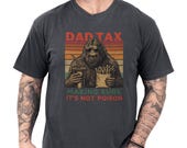 Photo 1 of 8: Charcoal Comfort Colors dad tax shirt with a retro sunset graphic of a sasquatch holding fries and a drink, cheeky "making sure it's not poison" tagline — nostalgic bigfoot dad tee and funny dad tee, cozy vintage look ideal Father's Day gift or gifts for dad for backyard BBQs and everyday wear