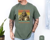 Photo 5 of 8: Soft blue jean tee with retro sunset stripes featuring a sunglasses-wearing sasquatch holding fries and a drink and bold Dad Tax It's Not Poison humor — a funny dad shirt and sasquatch shirt ideal as a casual weekend dad shirt or camping dad gift tee for birthdays