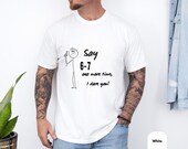 Photo 4 of 8: White minimalist stick figure tee on a relaxed male model, front print reads Say 6-7 one more time I dare you in bold black sketch style on soft cotton, cozy youthful casual tee perfect as a funny dare shirt, teacher gift tee or parent gag gift for teacher appreciation and everyday wear