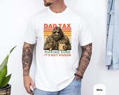 Photo 4 of 8: Soft moss green dad tax t shirt featuring a retro-striped sasquatch shirt graphic holding fries and a drink with cheeky "making sure it's not poison" caption, a funny dad shirt with vintage washed texture and cozy casual fit, ideal dad gift tee for camping, birthdays, or weekend wear