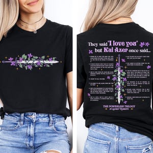 May include: Black t-shirt featuring a sword design with purple flowers and text. The front of the shirt displays the sword design, while the back has text that reads "They said 'I love you' but Kai Azer once said..." and a list of phrases.