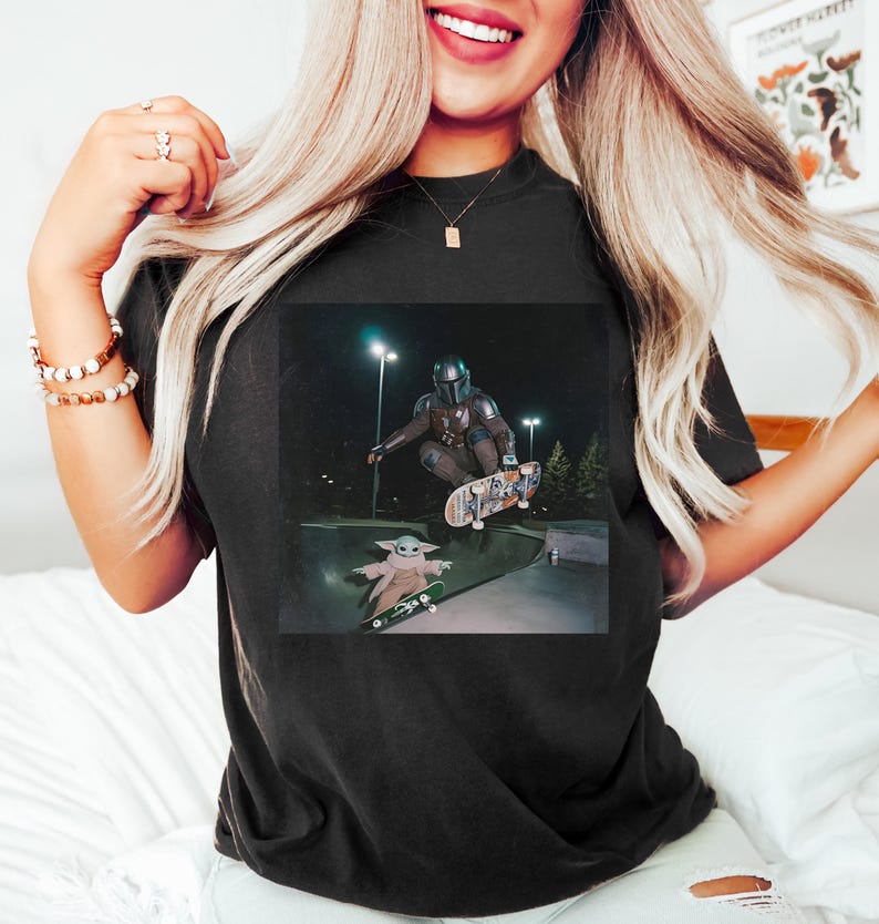 Puede incluir: Camiseta negra con un gr&aacute;fico de The Mandalorian y Grogu patinando en un skatepark por la noche. La imagen muestra a los personajes en el aire sobre monopatines, con Grogu en una tabla m&aacute;s peque&ntilde;a.