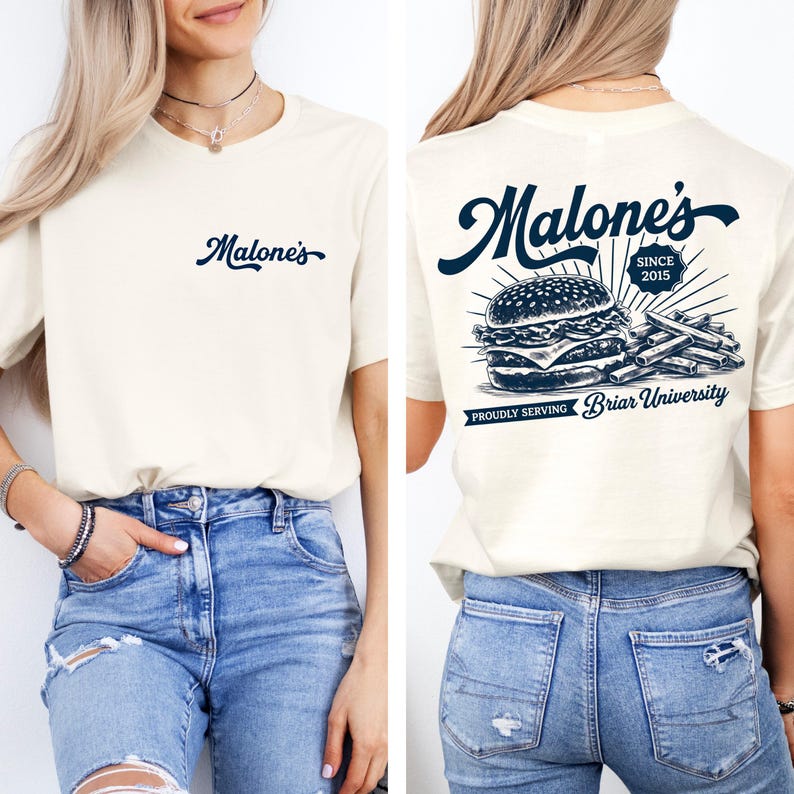 May include: Cream-colored t-shirt with the word "Malone's" in navy blue script on the front. The back features a navy blue graphic of a burger and fries, with the text "Malone's Since 2015" and "Proudly Serving Briar University."