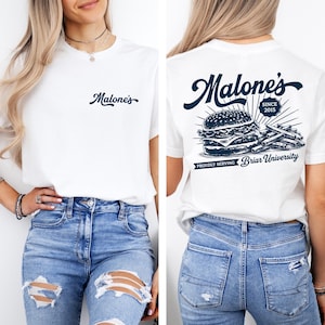 May include: White t-shirt with the word "Malone's" in navy blue script on the front. The back of the shirt features a burger and fries graphic with the text "Malone's Since 2015" and "Proudly Serving Briar University."