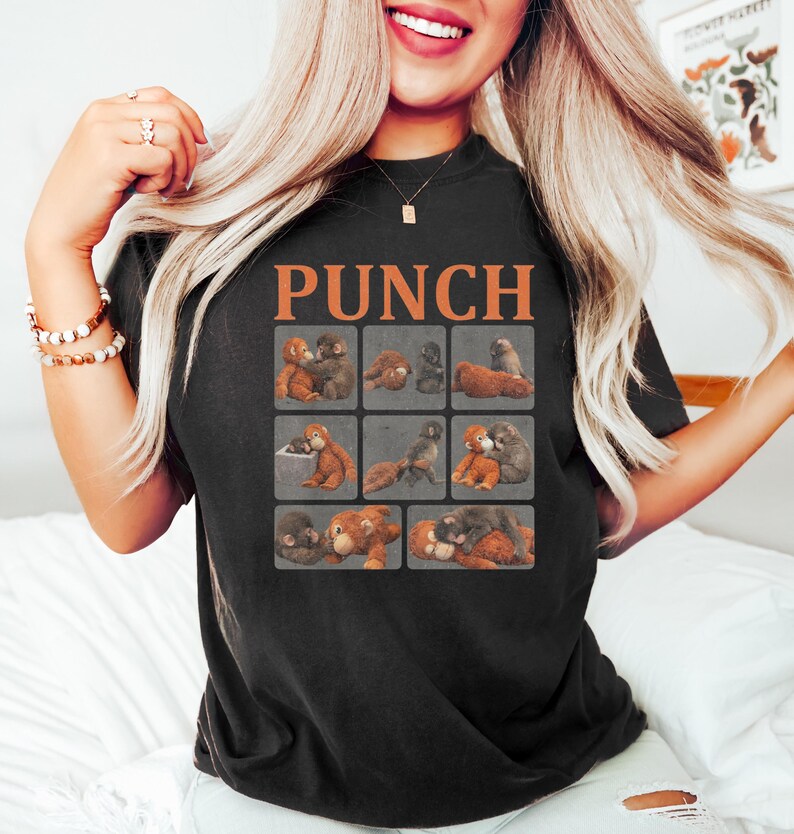 May include: Black t-shirt with the word "PUNCH" in orange block letters. The shirt features a grid of nine images of cartoon monkeys in various poses. The monkeys are in shades of brown and gray.