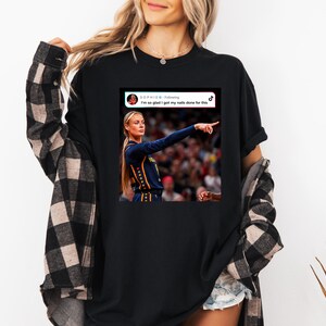 May include: A black t-shirt featuring a graphic print of a social media post. The graphic shows a basketball player in a dark blue jersey pointing, with the text "SOPHIE B - Following" and "I'm so glad I got my nails done for this" above the image.