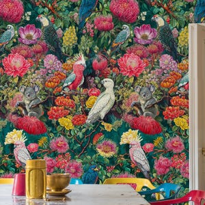 Könnte beinhalten: Ein Esszimmer mit einer lebendigen floralen Tapete mit Papageien, Koalas und exotischen Blumen in Rosa, Rot, Gelb und Grün. Ein Holztisch und bunte Stühle vervollständigen die Szene.