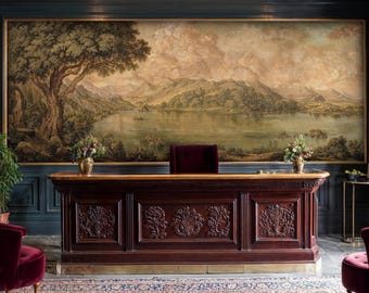 Op de afbeelding: Een grote, donkere houten bureau met sierlijke gravures en een groot landschapsschilderij erboven. De kamer heeft donkerblauwe panelen, een bordeauxrode stoel en een goudomrande spiegel, wat een luxe, vintage esthetiek creëert.
