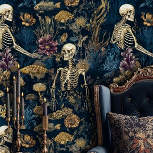 K&ouml;nnte beinhalten: Dunkelblaue Tapete mit einem botanischen und Skelett-Design. Goldfarbene Fisch- und Blumenelemente vor tiefblauem Hintergrund. Ein goldener Kerzenst&auml;nder mit schwarzen Kerzen und ein blauer Sessel im Vordergrund.