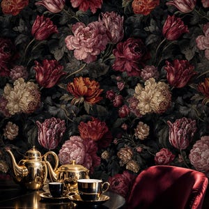 May include: A dark floral wallpaper featuring large, colorful flowers in shades of red, pink, and cream. A gold tea set with black cups and saucers sits on a round table, with a red velvet chair in the foreground.