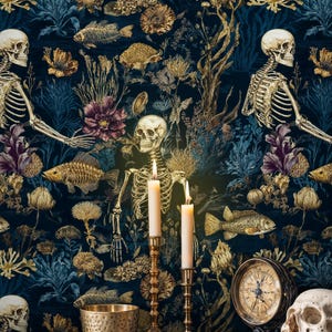K&ouml;nnte beinhalten: Dunkelblaue Tapete mit einem sich wiederholenden Muster aus goldenen Skeletten, Fischen und floralen Elementen. Zwei brennende Kerzen in goldenen Haltern stehen vor der Tapete. Ein Totenkopf, ein Kompass und Muscheln liegen auf einer Holzoberfl&auml;che.