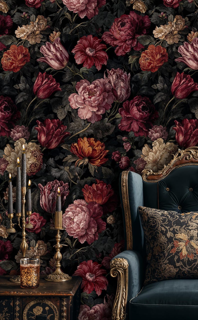 May include: A dark floral wallpaper featuring large, detailed flowers in shades of red, pink, and cream against a black background. A teal armchair with gold trim and a patterned pillow is in the corner. A gold candelabra with black candles and a glass of liquid are on a wooden table.