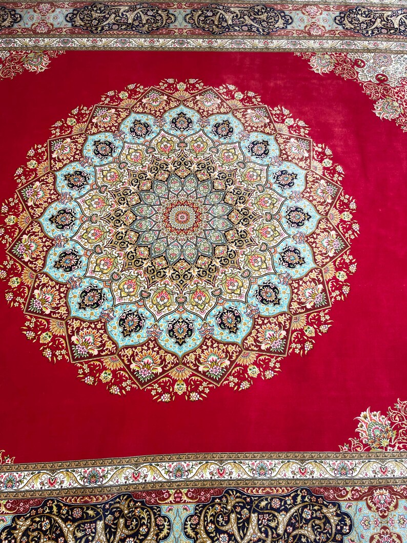 K&ouml;nnte beinhalten: Ein leuchtend roter Teppich mit einem aufwendigen zentralen Design. Das zentrale Medaillon weist ein komplexes Blumenmuster in Blau-, Gold- und Cremet&ouml;nen auf. Der Rand des Teppichs hat ein erg&auml;nzendes Design und schafft eine luxuri&ouml;se &Auml;sthetik.