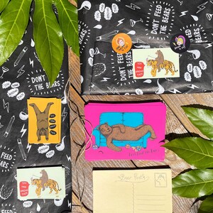 May include: A set of colorful postcards featuring illustrations of bears. The postcards have a pink, yellow, and green background. The postcards have the text "Don't Feed The Bears" and "Let's Feed The Bears".