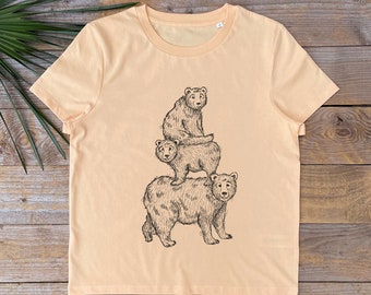 May include: A light peach t-shirt with a black and white illustration of three bears stacked on top of each other.