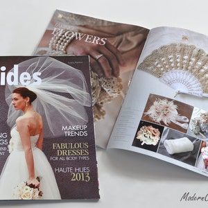 May include: A bridal magazine cover featuring a bride in a white wedding dress and veil, holding a bouquet of white flowers. The magazine title is "brides" and the text on the cover includes "Seven Stunning Weddings", "Makeup Trends", "Fabulous Dresses for All Body Types", and "Haute Hues 2013".