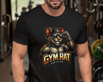 Könnte beinhalten: Schwarzes T-Shirt mit einer Cartoon-Illustration einer muskulösen Ratte mit Sonnenbrille und Kappe. Der Text "GYM RAT CERTIFIED" ist in Gold und Orange dargestellt. Das T-Shirt ist wahrscheinlich aus atmungsaktivem Material.