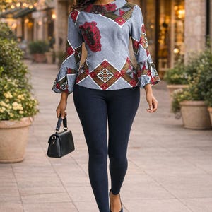 May include: A woman wearing a patterned gray blouse with bell sleeves, dark blue leggings, and black handbag. The blouse features red and brown geometric designs. She is also wearing dark blue flats.
