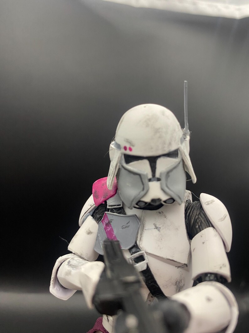 Pu&ograve; includere: Action figure bianca e grigia di un soldato con elmetto, armatura e fucile blaster. La figura ha accenti rosa sulla spalla e sul casco. La figura &egrave; in posa da battaglia, con il fucile puntato in avanti.