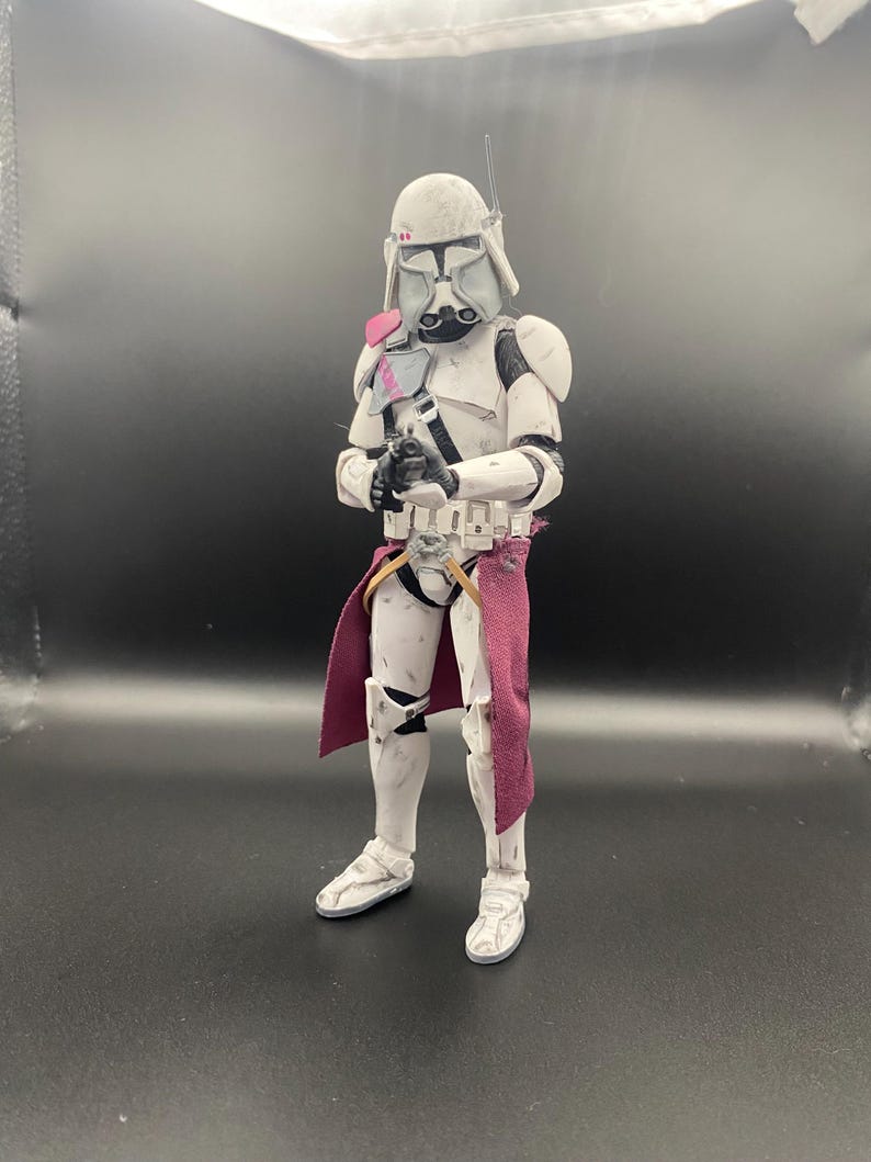 Pu&ograve; includere: Action figure bianca e grigia di un soldato in armatura, con un'arma nera. La figura ha un elmetto, spalline e una sciarpa bordeaux. La figura &egrave; su una superficie scura.