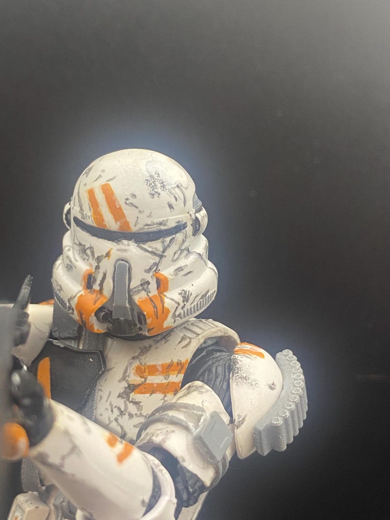 Pu&ograve; includere: Action figure dettagliata di un clone trooper di Star Wars. La figura &egrave; prevalentemente bianca con segni arancioni e dettagli usurati dalla battaglia. Il casco e l'armatura sono progettati in modo intricato.
