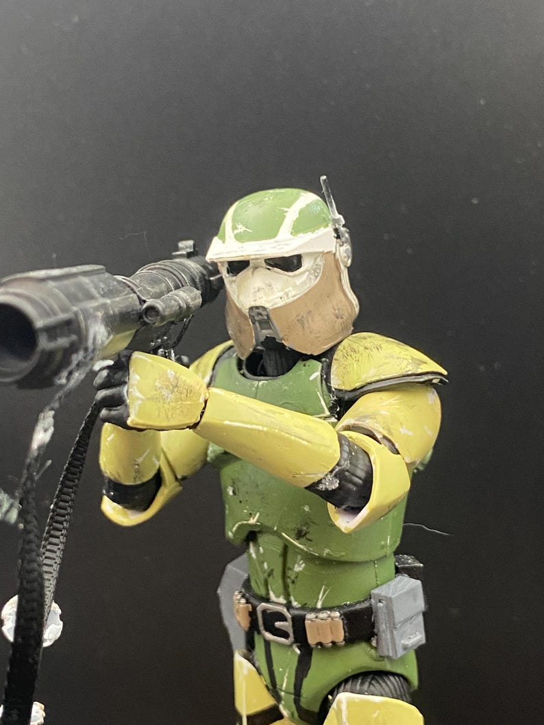 Pu&ograve; includere: Action figure dettagliata di un soldato in armatura verde e gialla, che tiene in mano una grande arma nera. L'elmetto &egrave; verde e bianco, con una copertura per il viso marrone. La figura &egrave; in posa come se stesse mirando l'arma.