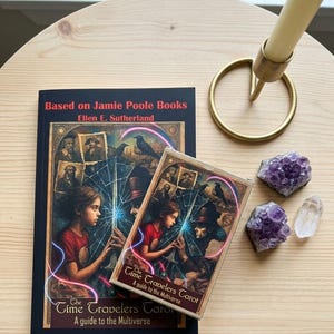 May include: A book and a deck of cards titled The Time Travelers Tarot: A guide to the Multiverse, based on Jamie Poole Books by Ellen E. Sutherland. The cover art features a person and a figure in a top hat with a glowing blue light.