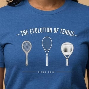 Könnte beinhalten: Ein blaues T-Shirt mit einer weißen Grafik von drei verschiedenen Tennisschlägern in einer Reihe. Über den Schlägern steht der Text THE EVOLUTION OF TENNIS und darunter der Text SINCE 1600. Die Schläger zeigen eine Designentwicklung.