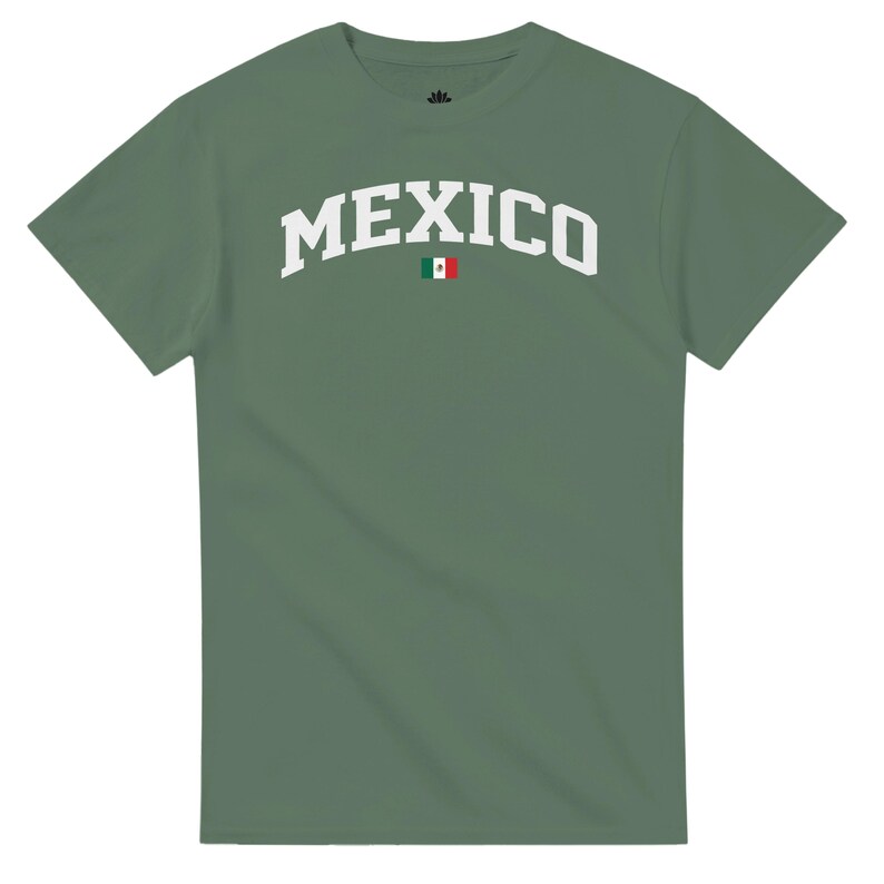 Puede incluir: Una camiseta verde salvia con la palabra "MEXICO" en letras blancas arqueadas. La bandera mexicana est&aacute; centrada debajo del texto. La camiseta tiene mangas cortas y cuello redondo.