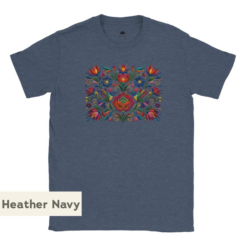 May include: A heather navy short-sleeve t-shirt featuring a central, colorful embroidered-style graphic of hummingbirds, various flowers, and swirling foliage in shades of red, orange, yellow, blue, and green. The text Heather Navy is visible.