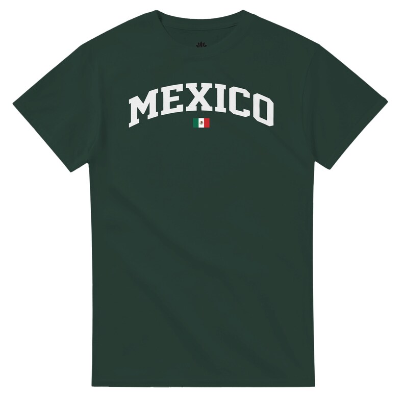 Puede incluir: Camiseta verde oscuro con la palabra "MEXICO" en blanco, arqueada sobre el pecho. Un peque&ntilde;o gr&aacute;fico de la bandera mexicana est&aacute; centrado debajo del texto. La camiseta tiene mangas cortas y cuello redondo.