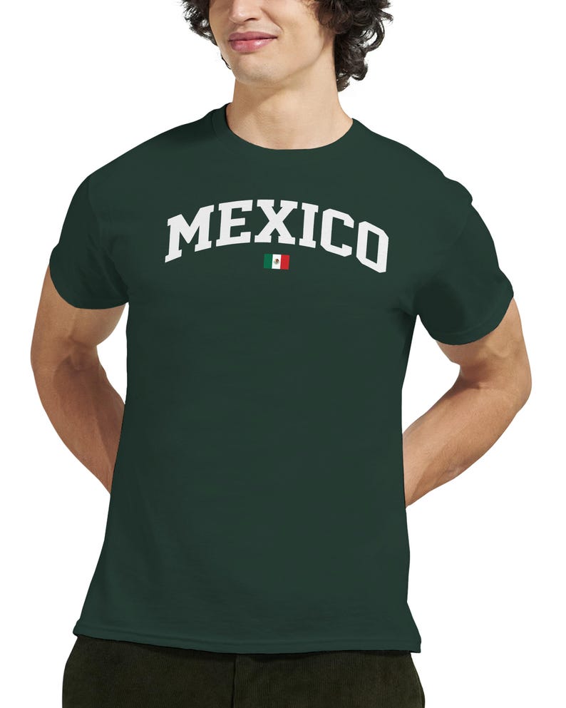 Puede incluir: Camiseta verde oscuro con la palabra "MEXICO" en letras blancas en el pecho. Una peque&ntilde;a bandera mexicana est&aacute; colocada debajo del texto. La camiseta es de cuello redondo.