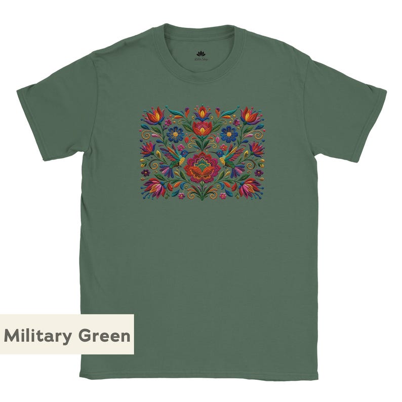 May include: A military green short-sleeve t-shirt featuring a central rectangular graphic print of colorful flowers, leaves, and two hummingbirds in shades of red, blue, yellow, and pink. The shirt has a crew neckline and a small logo on the inner neck.