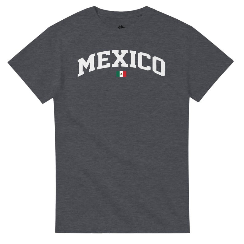 Puede incluir: Camiseta gris oscuro con la palabra "MEXICO" en blanco, con letras arqueadas. Una peque&ntilde;a bandera mexicana est&aacute; centrada debajo del texto. La camiseta es de cuello redondo.