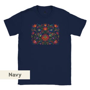 May include: A navy blue short-sleeve t-shirt featuring a central graphic print of colorful hummingbirds surrounded by vibrant red, orange, yellow, and blue flowers and green foliage. The design is symmetrical and detailed with intricate patterns.