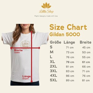 Puede incluir: Camiseta blanca Gildan 5000 con una tabla de tallas. La tabla muestra medidas en cent&iacute;metros para las tallas S a 5XL, incluyendo largo y ancho. La camiseta tiene el logo de Lillis Shop.