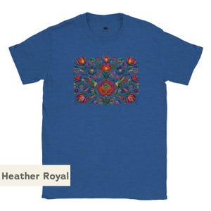 May include: A heather royal blue short-sleeve t-shirt featuring a central graphic print of colorful flowers and two hummingbirds in shades of red, orange, yellow, and green. The design is symmetrical with intricate floral patterns and foliage.