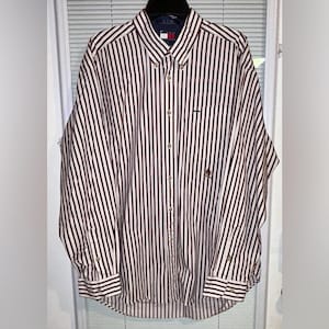 May include: A button-down shirt with vertical stripes in burgundy and white. The long-sleeved shirt has a button-down collar and a small logo on the chest. The shirt is hanging on a hanger.
