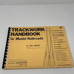 May include: A spiral-bound book titled Trackwork Handbook for Model Railroads by Paul Mallery. The yellow cover features black text, a technical track diagram, and a list of contents including NMRA standards, bench work, and layout design.