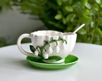 Taza y platillo de porcelana hechos a mano con diseño de lirio de los valles y cuchara.